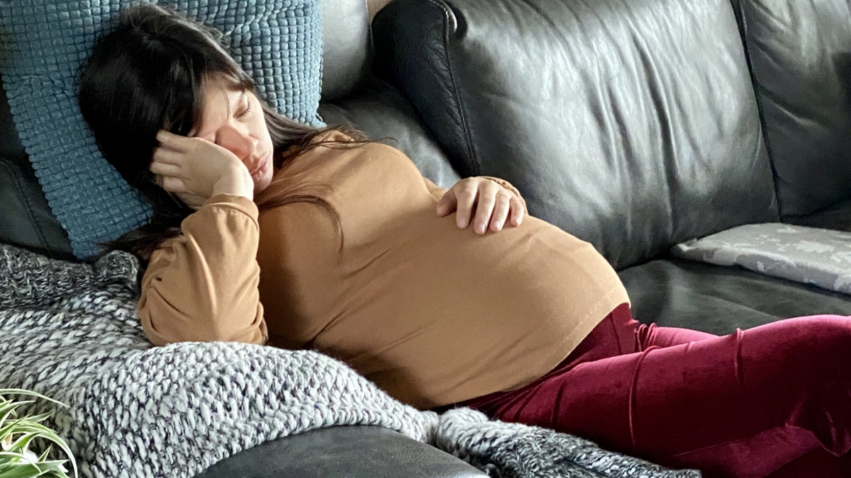 schwangere Frau liegt ersch&ouml;pft auf der Couch