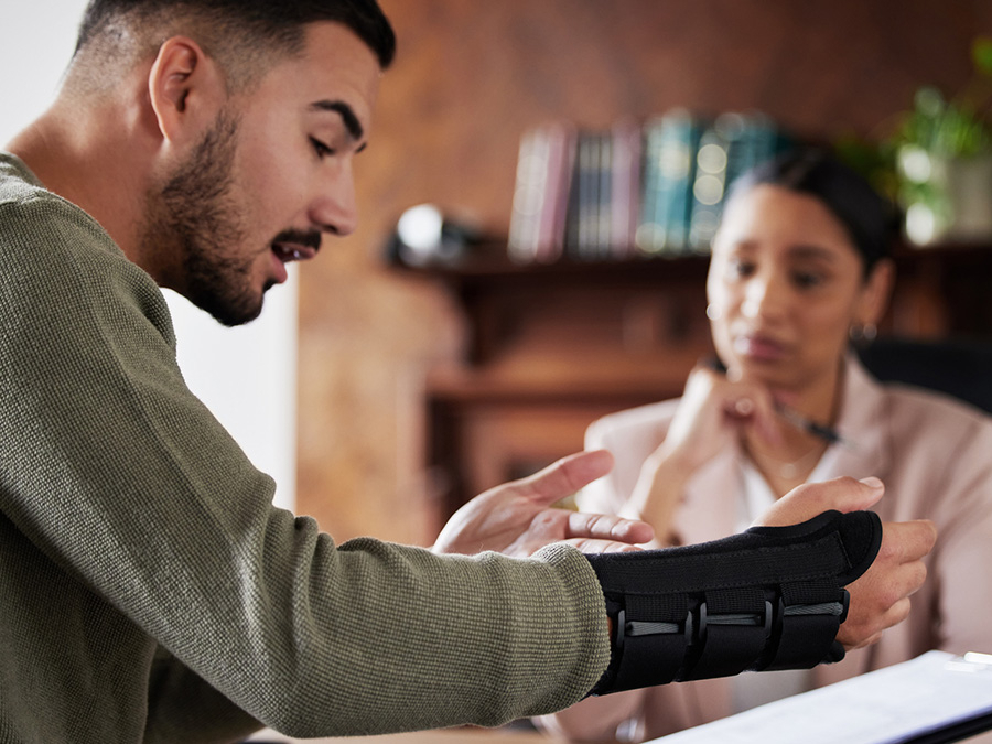 Mann mit gebrochenem Arm bereitet mit Anw&auml;ltin Dokumente f&uuml;r die Versicherung vor