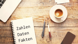 Das Bild zeigt ein Tisch auf dem ein Notebook, ein Block und eine Kaffeetasse stehen.