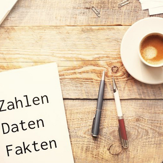 Das Bild zeigt ein Tisch auf dem ein Notebook, ein Block und eine Kaffeetasse stehen.