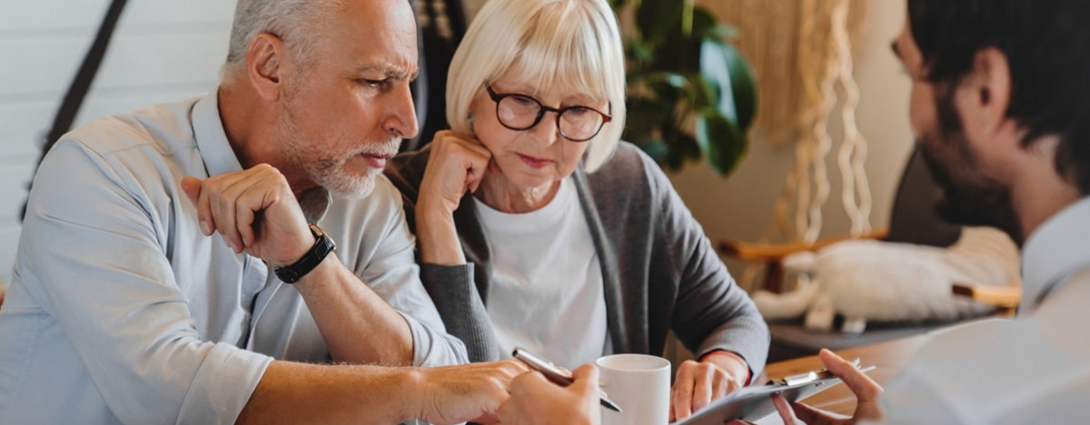 Ein Anwalt erkl&auml;rt einem Rentnerpaar wichtige Unterlagen.