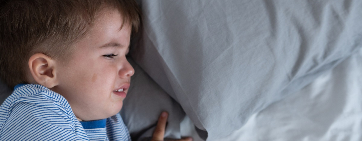 Kleiner Junge liegt in Bett, quengelt und schl&auml;ft nicht.
