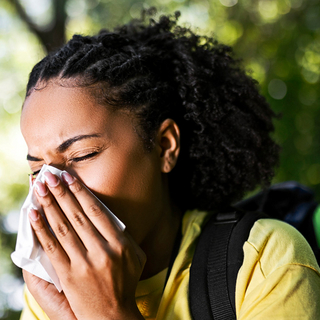 Junge Wandererin mit Allergie niest mit Taschentuch