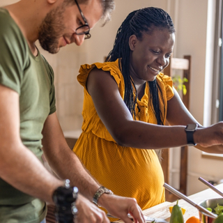 Mann und schwangere Frau kochen gemeinsam und lachen