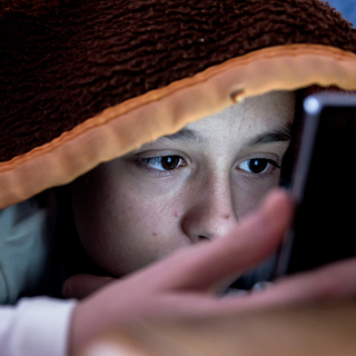 M&auml;dchen im Bett starrt auf ihr Smartphone