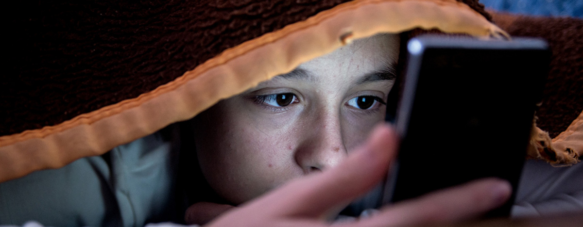 M&auml;dchen im Bett starrt auf ihr Smartphone