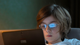 Kind mit Brille spielt auf dem Tablet