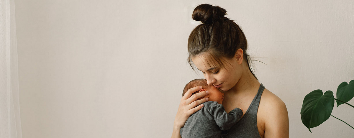 Junge Frau h&auml;lt Baby in ihrem Arm