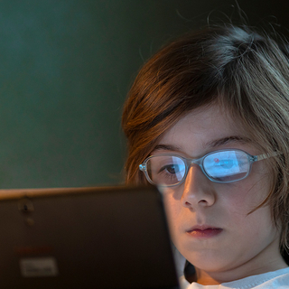 Kind mit Brille spielt auf dem Tablet