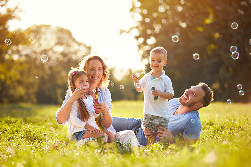 Junge Familie im sommerlichen Park beim Seifenblasen