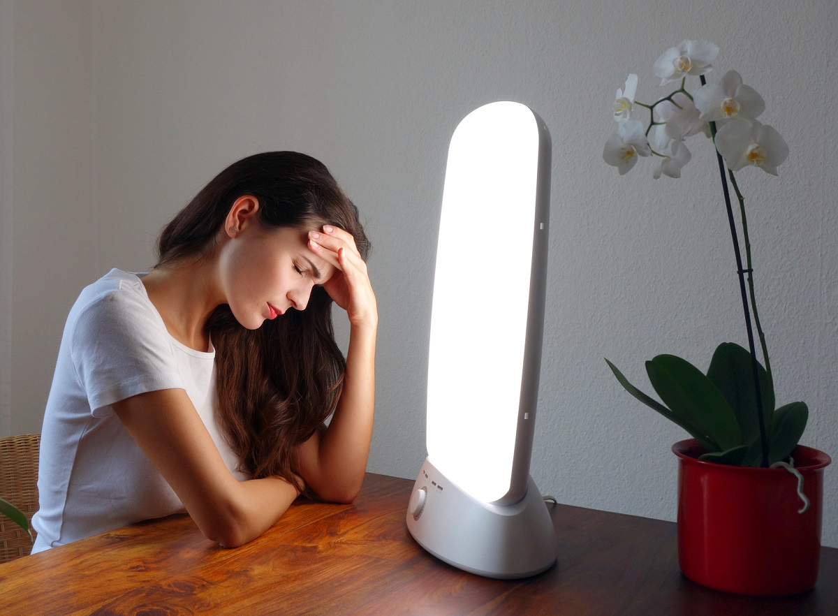 Eine Frau sitzt vor einer Tageslichtlampe f&uuml;r die Lichttherapie