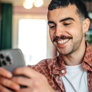 Fr&ouml;hlicher Mann mit Schnurrbart spielt am Handy