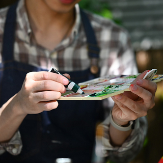 K&uuml;nstler in Sch&uuml;rze mischt Farben auf Palette f&uuml;r sein neues Projekt