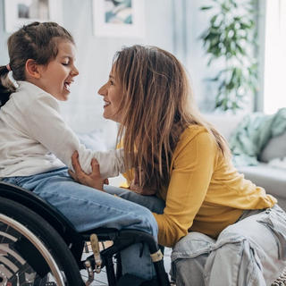 Mutter und kleine Tochter im Rollstuhl zu Hause