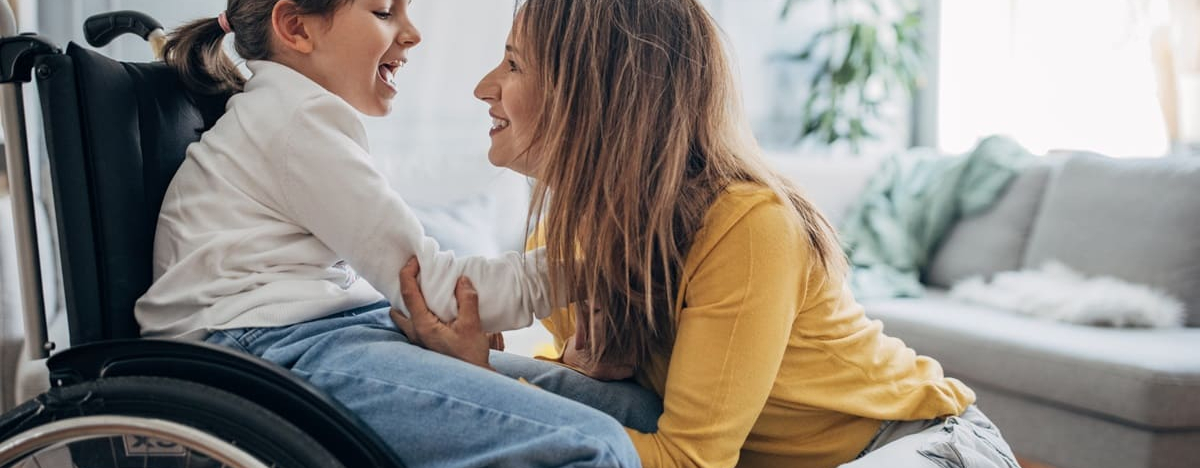 Mutter und kleine Tochter im Rollstuhl zu Hause