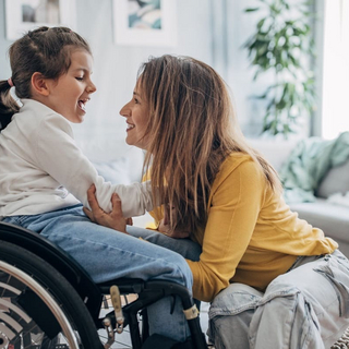 Mutter und kleine Tochter im Rollstuhl zu Hause