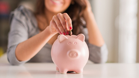 Frau steckt M&uuml;nze in ein Sparschwein