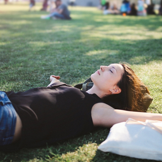 Frau liegt im Park auf der Wieso und sonnt sich
