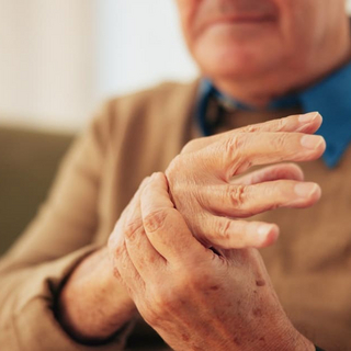 Haus, H&auml;nde und &auml;lterer Mann mit Handgelenksschmerzen, Arthritis und Entz&uuml;ndungen mit Karpaltunnelsyndrom. Nahaufnahme, Rentner oder &auml;ltere Person mit Osteoporose, Fibromyalgie oder Parkinson in der Lounge