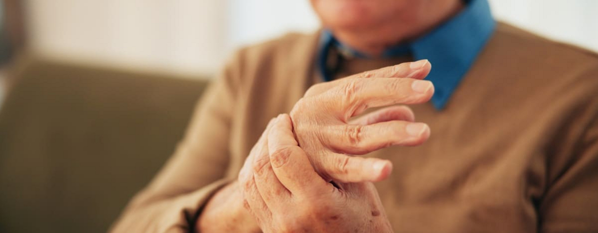 Haus, H&auml;nde und &auml;lterer Mann mit Handgelenksschmerzen, Arthritis und Entz&uuml;ndungen mit Karpaltunnelsyndrom. Nahaufnahme, Rentner oder &auml;ltere Person mit Osteoporose, Fibromyalgie oder Parkinson in der Lounge