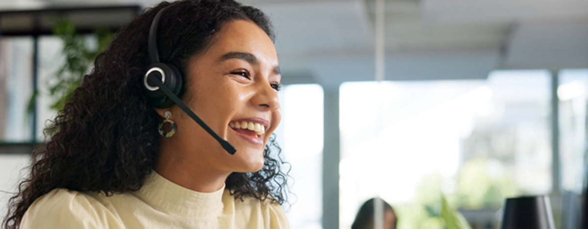 Lachende Frau telefoniert im Call-Center mit Kunden
