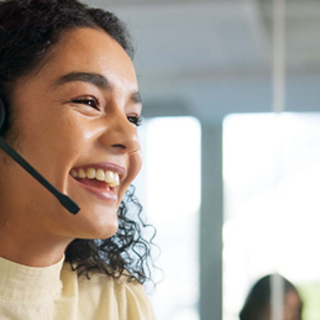 Lachende Frau telefoniert im Call-Center mit Kunden
