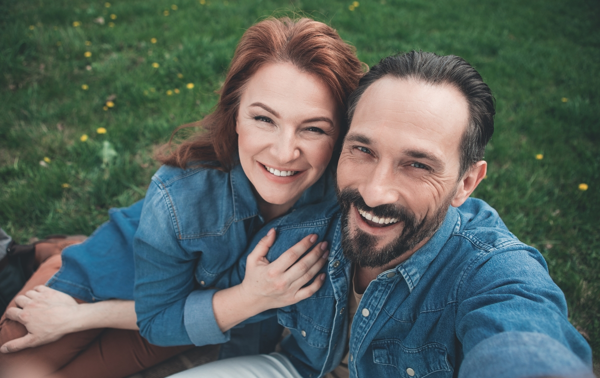 Verliebtes Paar sitzt auf einer Wiese und macht ein Selfie