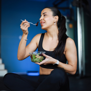 Eine junge Frau isst einen Salat nach dem Training.