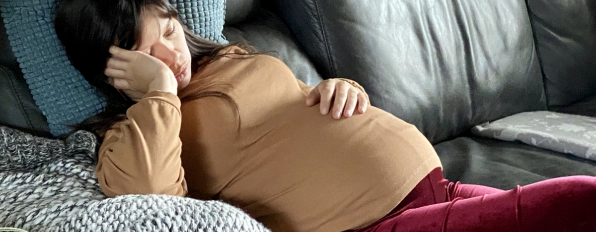 schwangere Frau liegt ersch&ouml;pft auf der Couch