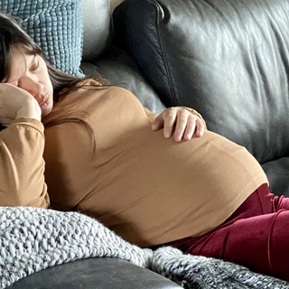 schwangere Frau liegt ersch&ouml;pft auf der Couch