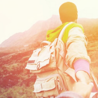 Das Bild zeigt ein Paar das Hand in Hand in der Landschaft steht. 