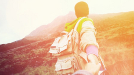 Das Bild zeigt ein Paar das Hand in Hand in der Landschaft steht. 