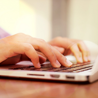 Bildausschnitt von H&auml;nden, die etwas in den Laptop eintippen.