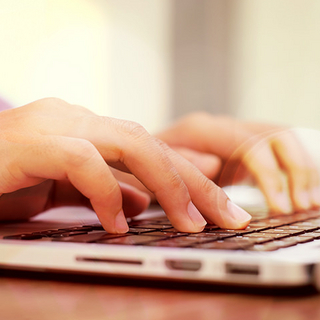 Bildausschnitt von H&auml;nden, die etwas in den Laptop eintippen.