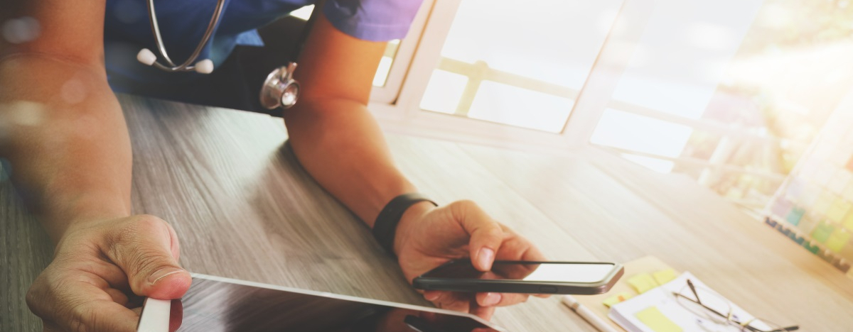 Arzt h&auml;lt mobiles Tablet und Smartphone in den H&auml;nden