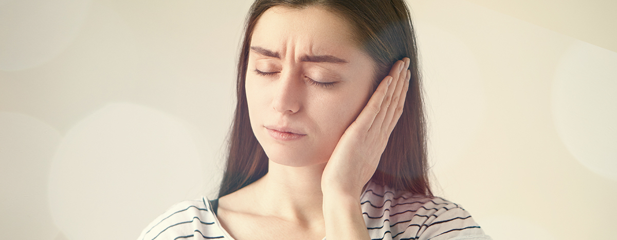 Frau h&auml;lt ihre Hand ans Ohr wegen des Tinnitus
