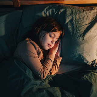 Kind schl&auml;ft im Bett
