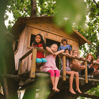 Eine Gruppe kleiner Kinder sitzt in einem Baumhaus