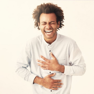 Junger Mann h&auml;lt sich vor Lachen den Bauch