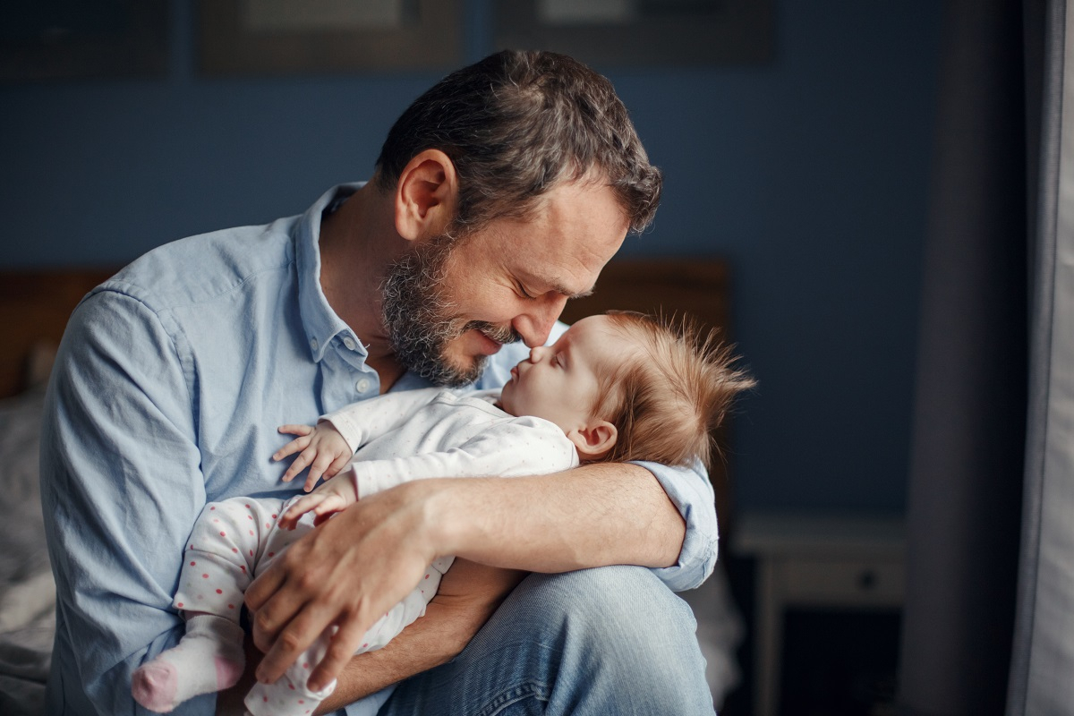 Vater hat sein Baby auf dem Arm und liebkost es
