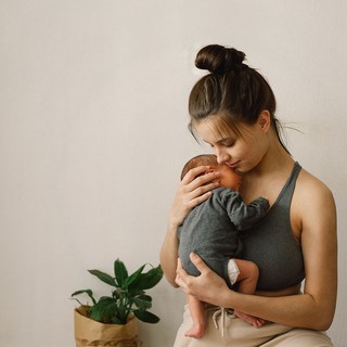 Junge Frau h&auml;lt Baby in ihrem Arm