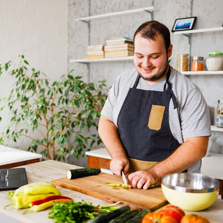 Gl&uuml;cklicher Mann, der gesundes Essen in der K&uuml;che kocht