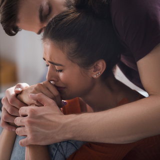 Weinende Frau, die von ihrem Partner umarmt wird