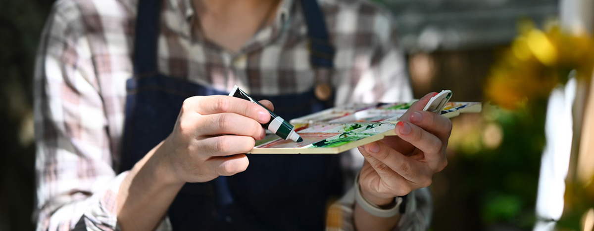 K&uuml;nstler in Sch&uuml;rze mischt Farben auf Palette f&uuml;r sein neues Projekt