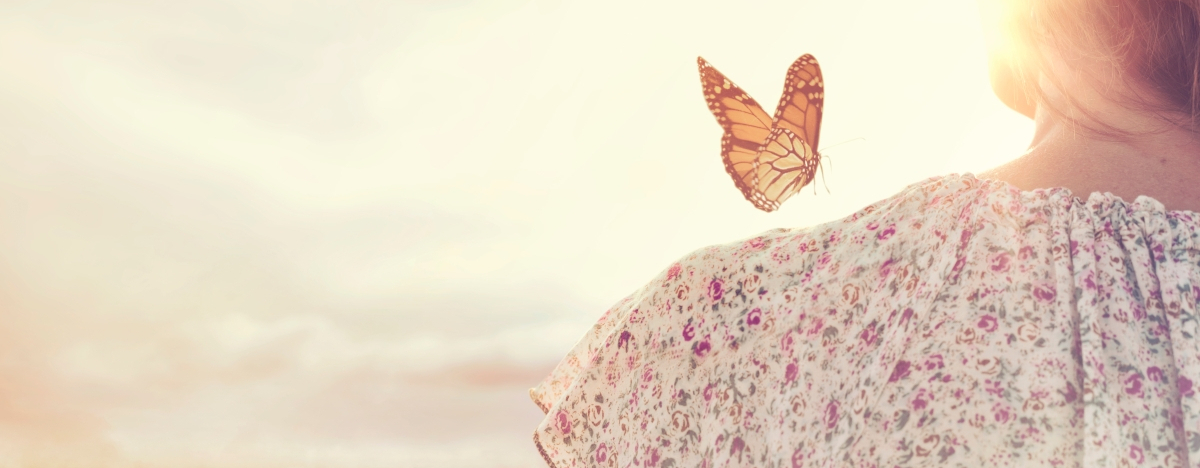 Schmetterling sitzt auf der Schulter einer Frau