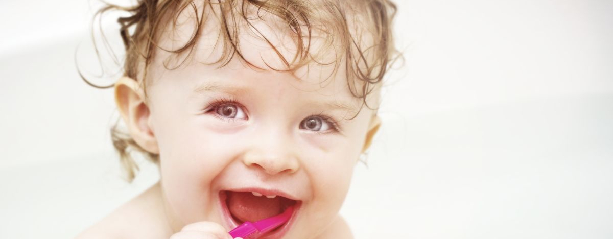 Baby sitzt in der Badewanne und putzt sich die Z&auml;hne