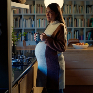 schwangere Frau steht nachts in der K&uuml;che und trinkt einen Tee