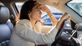 Eine gestresste Frau sitzt im Auto.