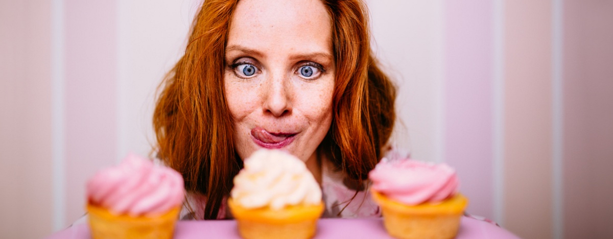 Junge Frau starrt vernarrt auf zuckrige Cupcakes.