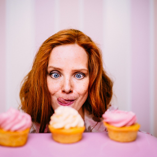 Junge Frau starrt vernarrt auf zuckrige Cupcakes.